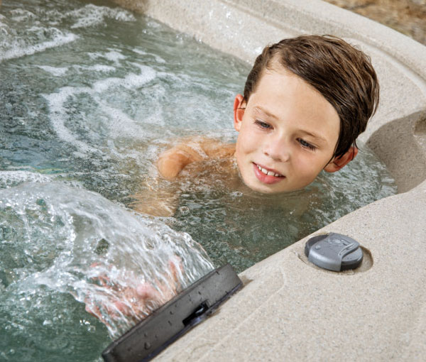 Child playing in waterfall on Cascina Hot Tub Spa | Freeflow Spas available at the Recreational Warehouse Southwest Florida (Naples, Fort Myers and Port Charlotte Locations) Pool Warehouse