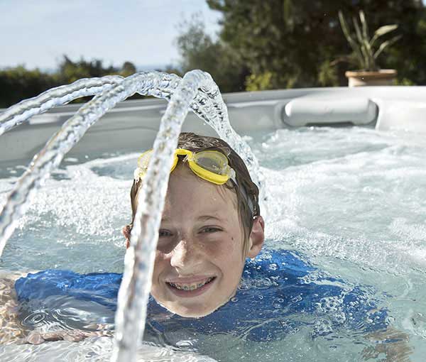 Child playing in Vanguard Hot Tub Spa with Waterfall | Hot Springs Spas available at the Recreational Warehouse Southwest Florida (Naples, Fort Myers and Port Charlotte Locations) Pool Warehouse